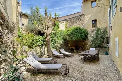 a patio with chairs and a table and a tree at La Marisol in LʼIsle-sur-la-Sorgue