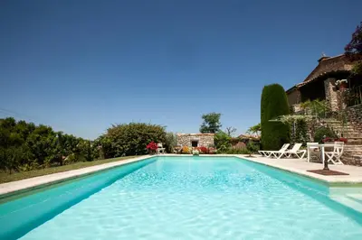 a swimming pool with blue water in front of a house at Chez Suzanne in Bonnieux