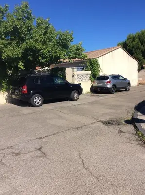 two cars parked in a parking lot next to a house at Ogooué Studio in Carpentras
