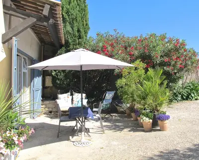 an umbrella and a table and chairs in a garden at les Lauriers in Caromb