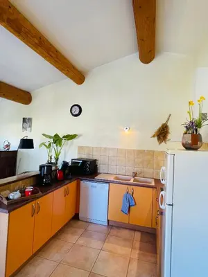 a kitchen with orange cabinets and a white refrigerator at Gîte Les Vignes in Carpentras