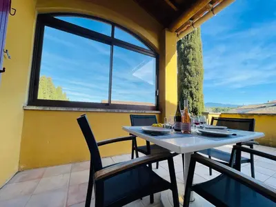 a table and chairs on a balcony with a window at Gîte Les Vignes in Carpentras