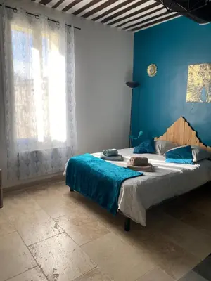 a bedroom with a large bed with a blue wall at Studio de charme le Clos de l'Etang + place de parking in LʼIsle-sur-la-Sorgue