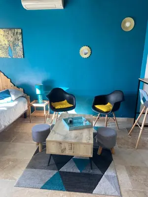 a living room with three chairs and a blue wall at Studio de charme le Clos de l'Etang + place de parking in LʼIsle-sur-la-Sorgue