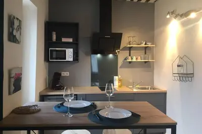 a kitchen with a wooden table with two wine glasses on it at Studio de charme le Clos de l'Etang + place de parking in LʼIsle-sur-la-Sorgue