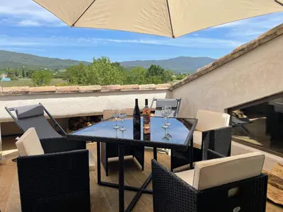 a table with wine bottles and glasses on a balcony at Appartement de charme Sud Luberon classé 4 étoiles in Puyvert