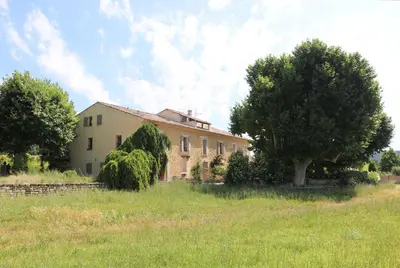 a building with a tree in front of a field at Appartement de charme Sud Luberon classé 4 étoiles in Puyvert