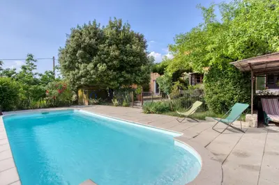 a swimming pool in a yard with two chairs at Mas de Bacalan in Mormoiron