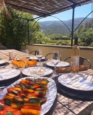 a wooden table with plates of food and wine glasses at VILLA BEL - Entre paradis et vignes in Ménerbes