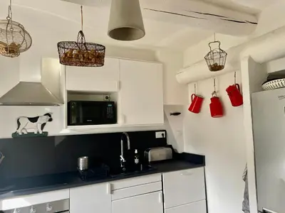a kitchen with white cabinets and a black counter top at VILLA BEL - Entre paradis et vignes in Ménerbes