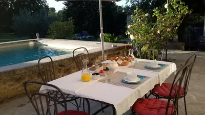 a table and chairs with a table and a pool at Chambres d'hôtes Le Vignoble in Cucuron