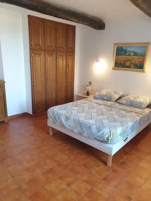 a bedroom with a bed and a wooden cabinet at Charmante maison de village au cœur du Luberon in Pierrevert