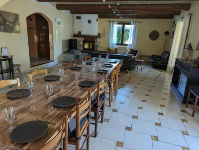 a large wooden table in a room with chairs and a living room at Gîte Les Murmures du Ventoux in Mormoiron