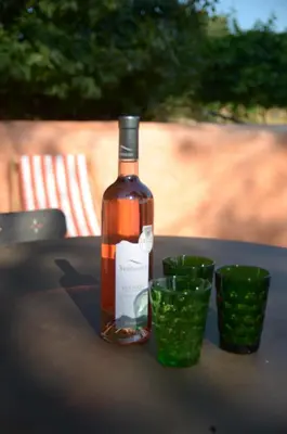 a bottle of wine sitting on a table with two green cups at Le petit Bacalan in Mormoiron