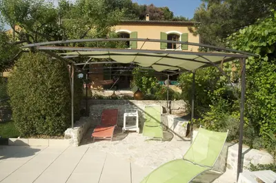 a group of lawn chairs under a pergola at Le petit Bacalan in Mormoiron