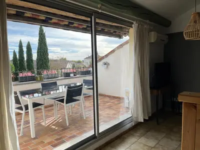 a room with a balcony with a table and chairs at Duplex lumineux sur gde TERRASSE, BALNEO double, parking privé, CLIM, local vélos in Entraigues-sur-la-Sorgue