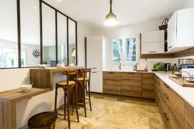 a kitchen with wooden cabinets and bar stools at Stunning house on the edge of the Luberon in Cheval-Blanc