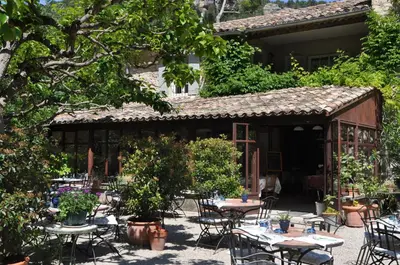 a patio with tables and chairs in front of a building at La Figuiere Fontaine de Vaucluse in Fontaine-de-Vaucluse