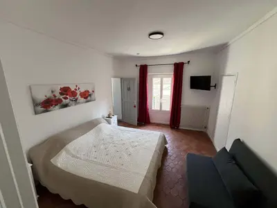 a bedroom with a bed and a couch and a window at La Figuiere Fontaine de Vaucluse in Fontaine-de-Vaucluse