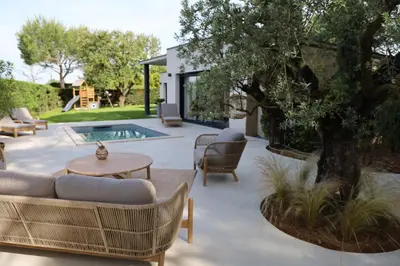 a patio with a tree and chairs and a table at Villa moderne en Provence avec piscine in Carpentras