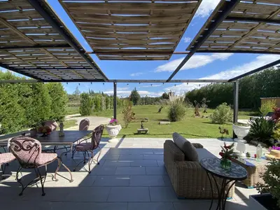 a patio with a table and chairs under a wooden pergola at Le Galinié Chic'Art. Un bel Atelier avec Piscine in Carpentras