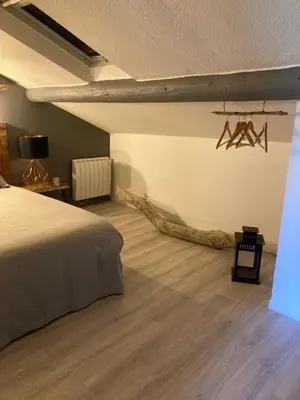 a bedroom with a bed and a log on the wall at Grande terrasse CLIM parking privé SMART TV, local velos in Entraigues-sur-la-Sorgue