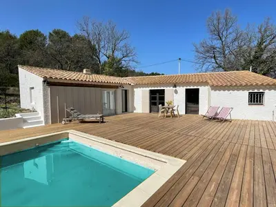 a house with a wooden deck and a swimming pool at Mas de la Pivoine in Le Puy-Sainte-Réparade