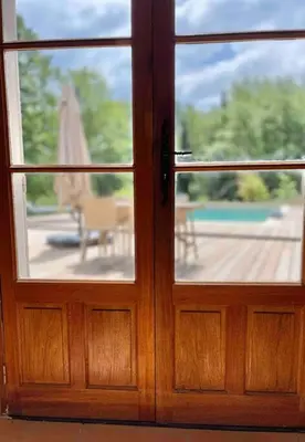 a door with a view of a patio with an umbrella at Mas de la Pivoine in Le Puy-Sainte-Réparade