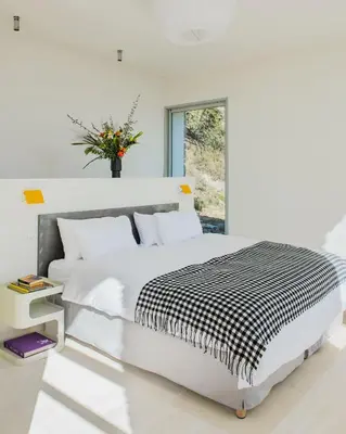 a white bedroom with a large bed and a vase of flowers at Les Milles Roches in Gordes