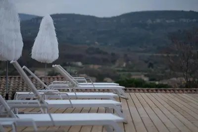 a row of lounge chairs and umbrellas on a roof at La Possibilité d'une Ile in Apt