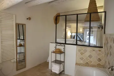 a bathroom with a tub and a mirror at LE PASSAGE in Lourmarin