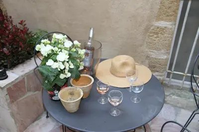 a table with a hat and wine glasses and flowers at LE PASSAGE in Lourmarin