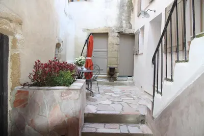 an alley with a table and a red umbrella at LE PASSAGE in Lourmarin