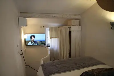 a bedroom with a bed and a tv on a wall at LE PASSAGE in Lourmarin
