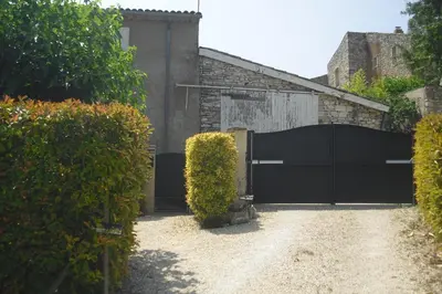a driveway with a black gate and bushes at Lou mas li Pitchoun 