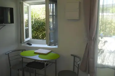 a small table with a book on it next to a window at Lou mas li Pitchoun 
