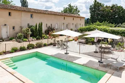 a swimming pool with umbrellas and a building at MAS PAPABIOU in Eygalières
