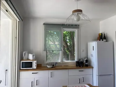a kitchen with a table and a refrigerator at Maison Avec jardin clôturé in LʼIsle-sur-la-Sorgue
