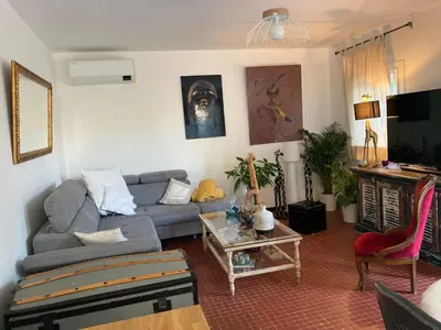 a living room with a couch and a table at Maison Avec jardin clôturé in LʼIsle-sur-la-Sorgue