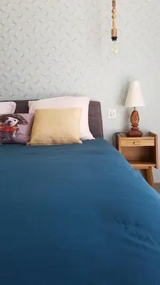 a bedroom with a blue bed with a lamp and a table at L’Abrico’thym in Apt