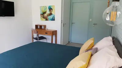 a bedroom with a bed and a table and a desk at L’Abrico’thym in Apt
