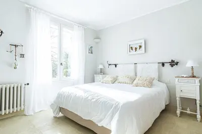 a white bedroom with a white bed and a window at Stunning property between Alpilles and Luberon in Cavaillon