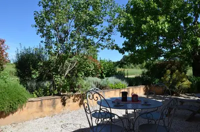 a table and chairs sitting in a garden at Le Mas Perréal in Saint-Saturnin-les-Apt