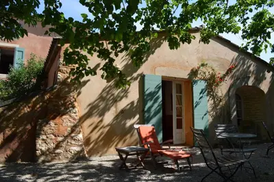 a house with chairs and a table in front of it at Le Mas Perréal in Saint-Saturnin-les-Apt