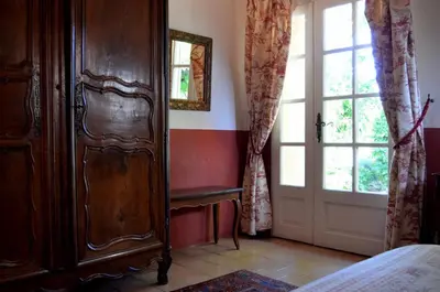 a bedroom with a large wooden cabinet and a window at Le Mas Perréal in Saint-Saturnin-les-Apt
