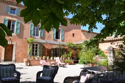 a patio with chairs and a table in front of a building at Le Mas Perréal in Saint-Saturnin-les-Apt