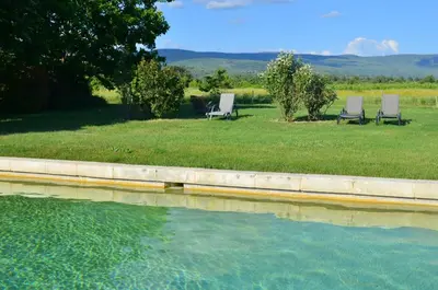 two chairs sitting in the grass next to a pool of water at Le Mas Perréal in Saint-Saturnin-les-Apt