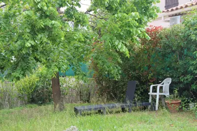 a white chair sitting in the grass next to a tree at Chambres d'hôtes Elisa & Etienne in Manosque