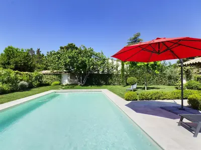 a pool with a red umbrella and a chair and a table with an umbrella at Villa rénovée à Eygalières avec piscine chauffée - FR-1-599-19 in Eygalières