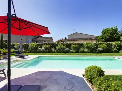 a swimming pool with a red umbrella next to a house at Villa rénovée à Eygalières avec piscine chauffée - FR-1-599-19 in Eygalières